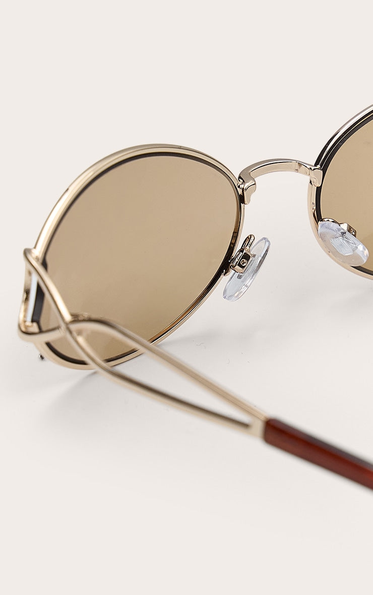 https://cdn-img.prettylittlething.com/1/2/d/6/12d6db2bb1dcf761888cf37190a964c4391e2a06_CNL7823_3_gold_oval_arm_detail_sunglasses.jpg