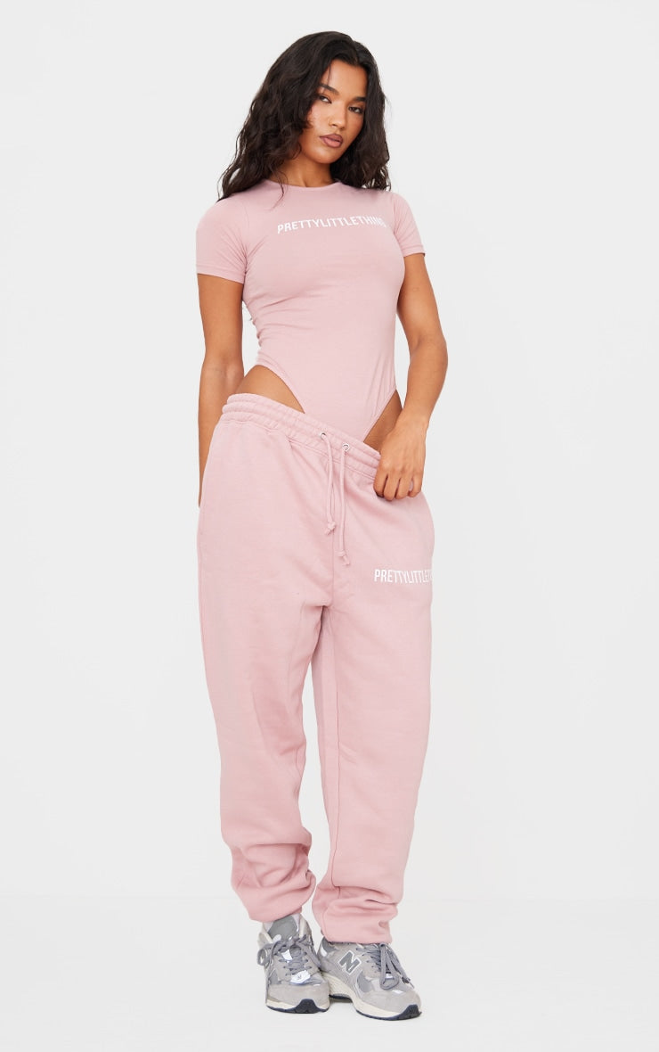 https://cdn-img.prettylittlething.com/1/3/9/8/1398c20be30c0a19d432ebba8c605cf4edf792d1_CNF2379_3_prettylittlething_light_pink_logo_short_sleeve_bodysuit.jpg