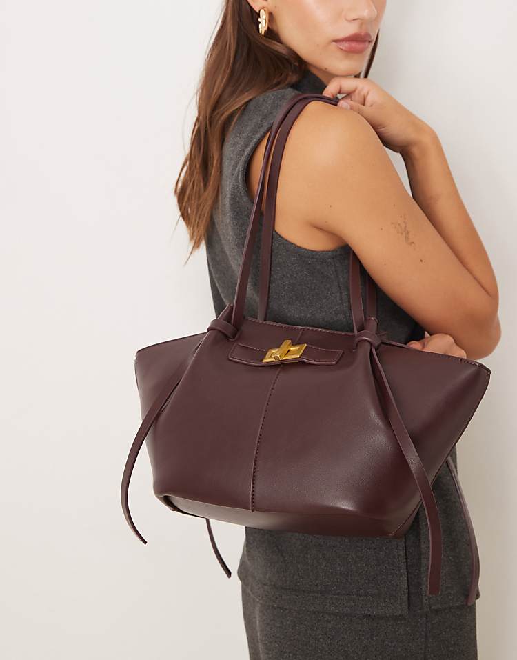 https://images.asos-media.com/products/gina-tricot-faux-leather-small-tote-bag-with-strap-and-clutch-detail-in-dark-red-burgundy/209114651-1-burgundy?$n_750w$&wid=750&fit=constrain